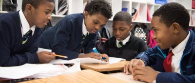Buffalo United Charter School, K-8 School in Buffalo NY: group of students huddled together discussing and assignment.