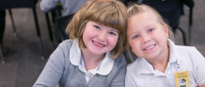 K-8 School in Ypsilanti: Two students smiling together in classroom.