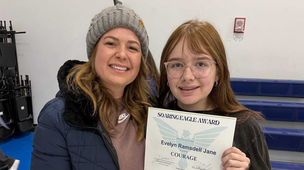 Student and parent smiling at an assembly