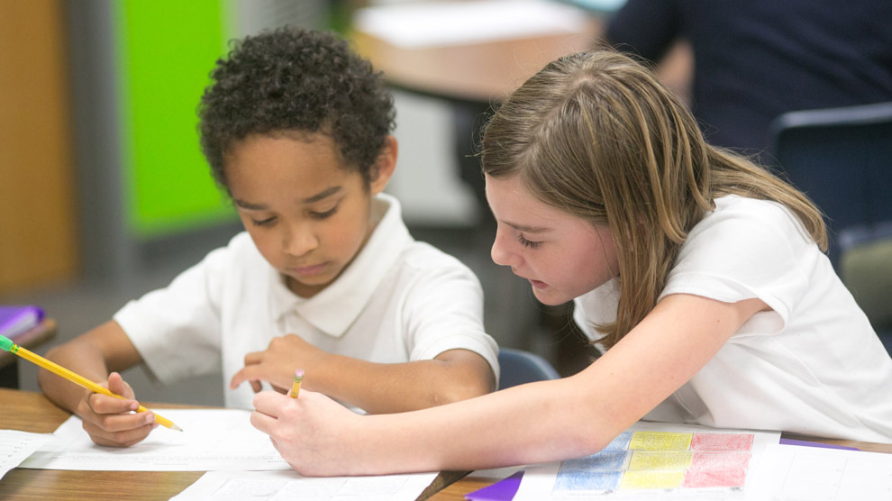 Two students smiling in front of their classroom lockers