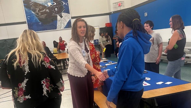 K-8 School in Dayton: Student talking with representative at a booth.