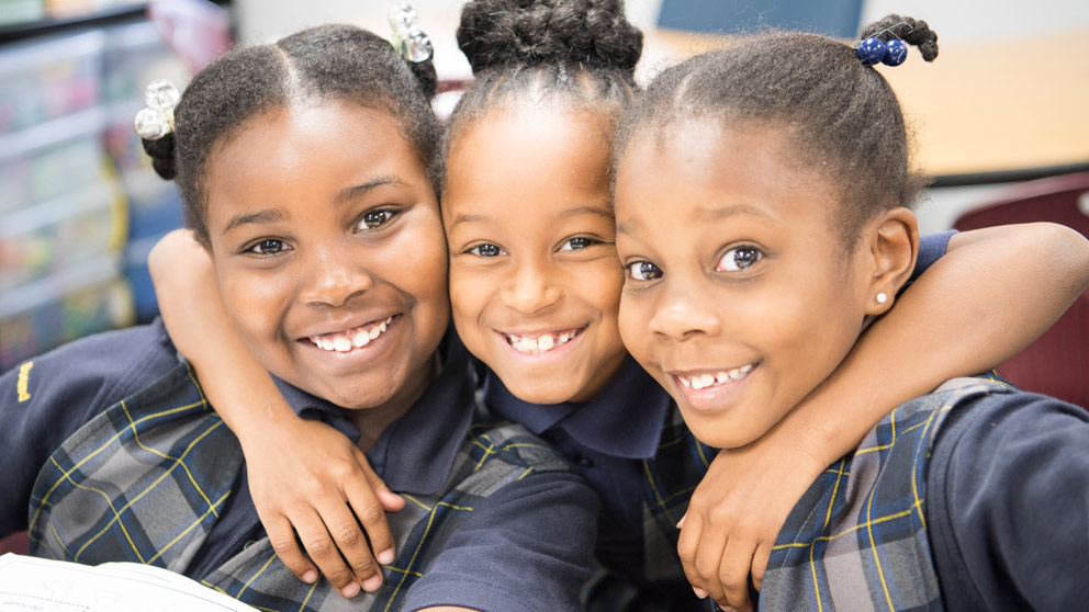 Two students smiling in front of their classroom lockers