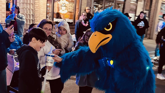 K-8 School in Brighton: Foundations mascot Ferry the Falcon passing out candy at parade.