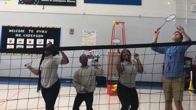 K-8 School in Milwaukee: Students and Anderson play badminton in gym.