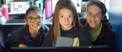 Three students smiling in classroom