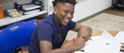 K-8 School in Toledo: Student smiling at desk, working on class work.