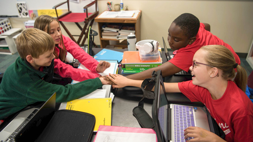 Students wearing red shirts, working together on a project.