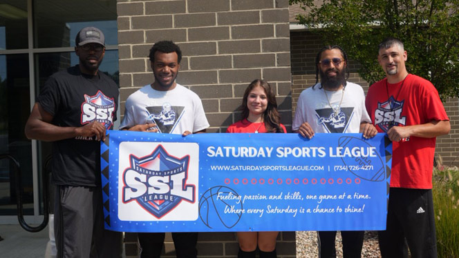 K-8 School in Canton: Grey poses with coaches and Saturday Sports League banner.