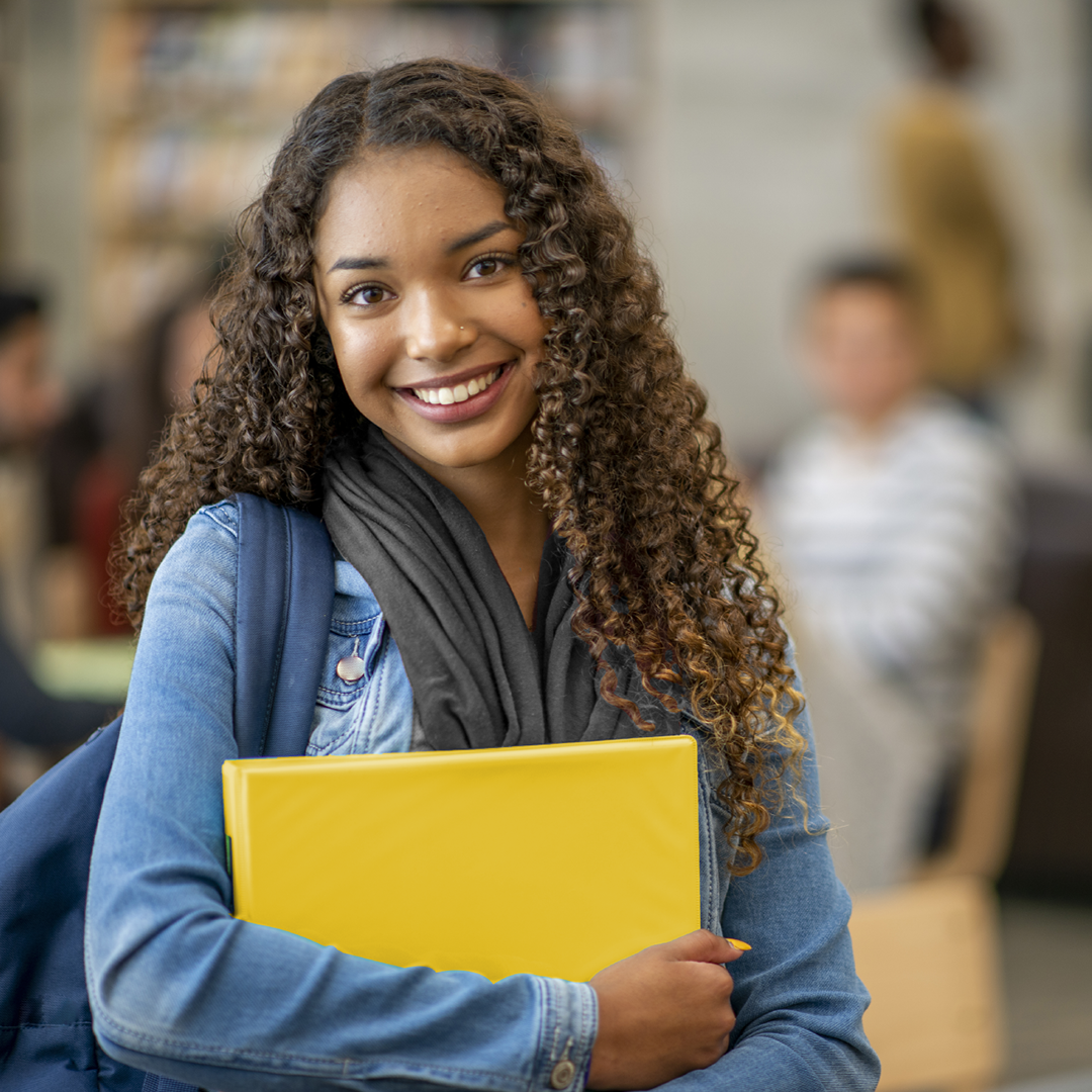 Girl student with yellow folder in her arms.