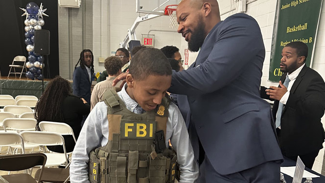 K-8 School in Brooklyn: FBI Agent helps Brooklyn Scholars student put on vest.