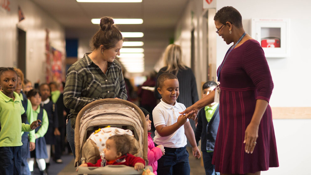 Parent and child talking with teacher in hallway