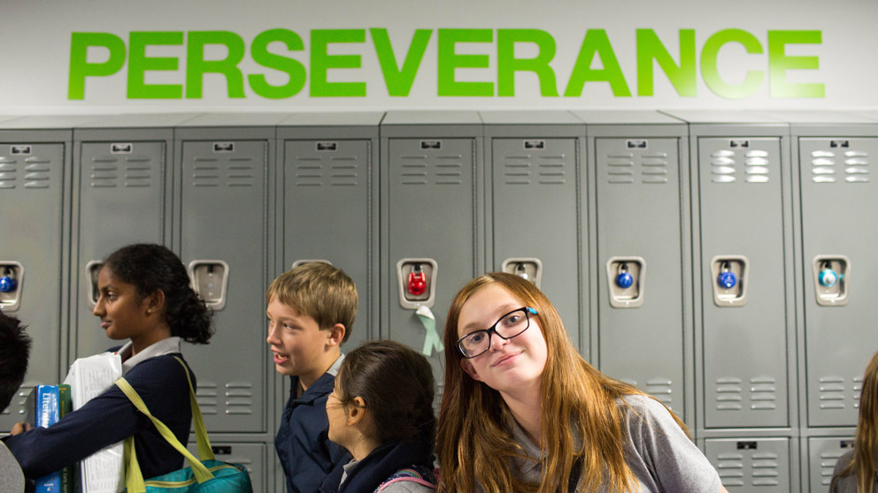 Two students smiling in front of their classroom lockers